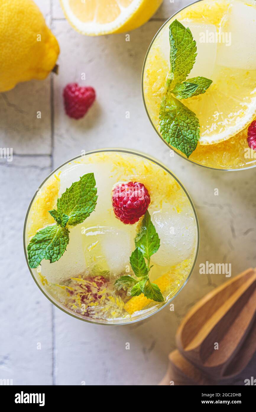 Hausgemachte Limonade mit Minze und Himbeeren in Gläsern, graue Fliesen Hintergrund, Draufsicht. Konzept für kalte Sommergetränke. Stockfoto