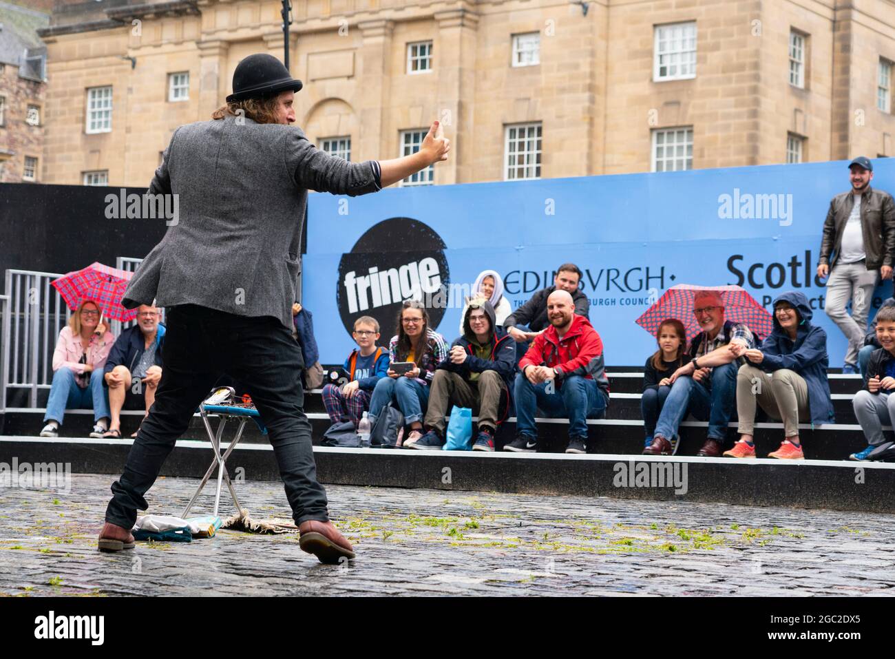 Edinburgh, Schottland, Großbritannien. August 2021. Bilder von der Royal Mile in der Altstadt von Edinburgh am Eröffnungstag des Edinburgh Fringe Festivals 2021. Das Festival sieht ganz anders aus als vor zwei Jahren. Nur sehr wenige Straßenaufführungsräume sind erlaubt und deutlich weniger Touristen sind zu sehen. Auch eine hohe Sichtbarkeit der Polizei, es gibt mehr Polizeibeamte als Darsteller auf der Straße, steht in einem deutlichen Kontrast zu den Vorjahren. PIC; Performer unterhält die Menge in speziell dafür eingerichteten, abgeschirmten Veranstaltungsräumen im Freien, die die Kapazität des Publikums einschränken. Iain Masterton/Alamy Live Nachrichten. Stockfoto