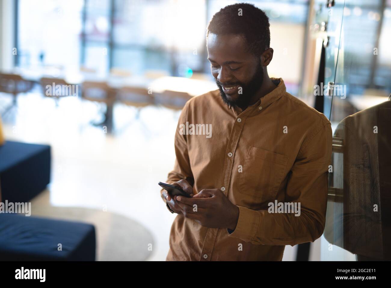 Lächelnder afroamerikanischer Geschäftsmann mit Smartphone und formeller Kleidung Stockfoto