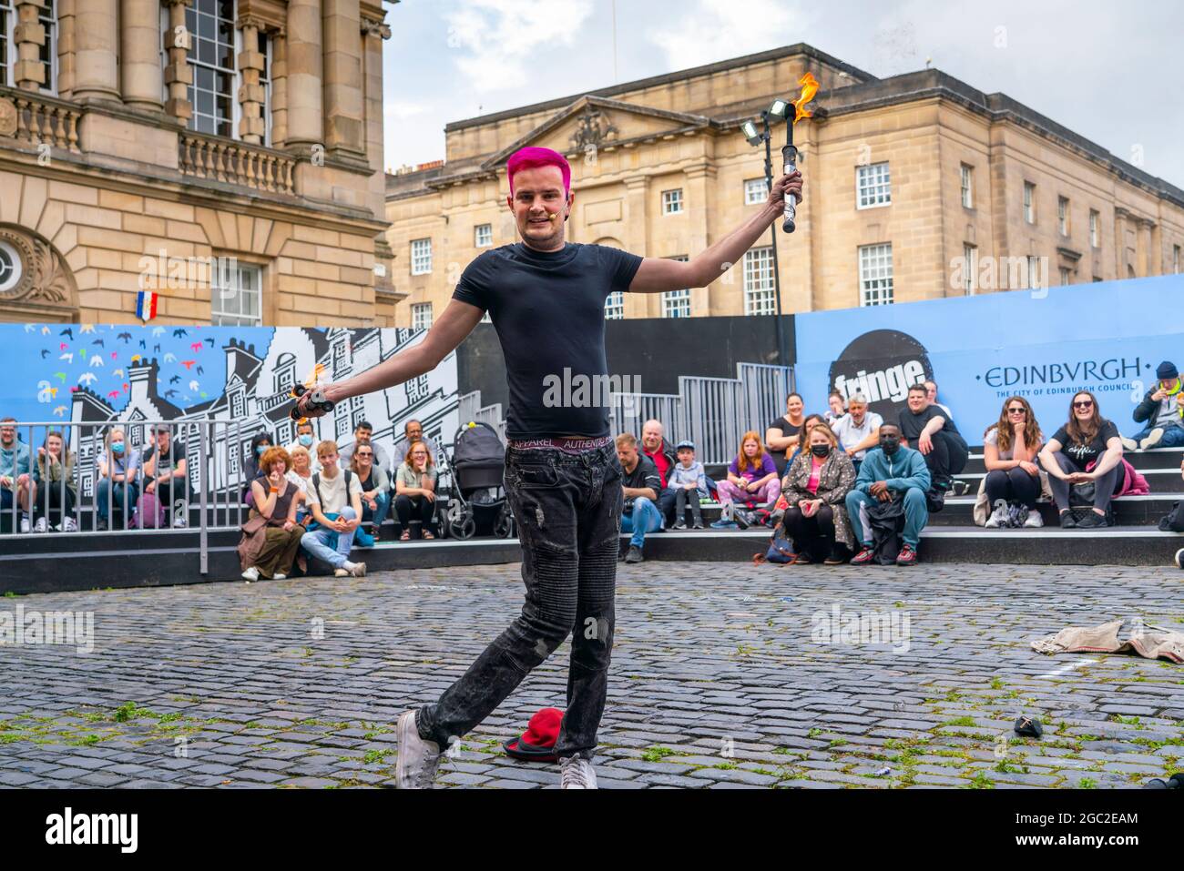 Edinburgh, Schottland, Großbritannien. August 2021. Bilder von der Royal Mile in der Altstadt von Edinburgh am Eröffnungstag des Edinburgh Fringe Festivals 2021. Das Festival sieht ganz anders aus als vor zwei Jahren. Nur sehr wenige Straßenaufführungsräume sind erlaubt und deutlich weniger Touristen sind zu sehen. Auch eine hohe Sichtbarkeit der Polizei, es gibt mehr Polizeibeamte als Darsteller auf der Straße, steht in einem deutlichen Kontrast zu den Vorjahren. PIC; Performer unterhält die Menge in speziell dafür eingerichteten, abgeschirmten Veranstaltungsräumen im Freien, die die Kapazität des Publikums einschränken. Iain Masterton/Alamy Live Nachrichten. Stockfoto