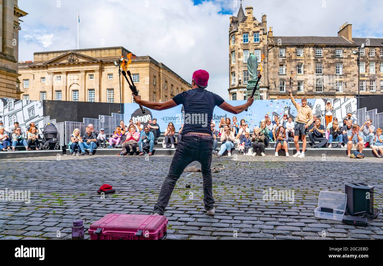 Edinburgh, Schottland, Großbritannien. August 2021. Bilder von der Royal Mile in der Altstadt von Edinburgh am Eröffnungstag des Edinburgh Fringe Festivals 2021. Das Festival sieht ganz anders aus als vor zwei Jahren. Nur sehr wenige Straßenaufführungsräume sind erlaubt und deutlich weniger Touristen sind zu sehen. Auch eine hohe Sichtbarkeit der Polizei, es gibt mehr Polizeibeamte als Darsteller auf der Straße, steht in einem deutlichen Kontrast zu den Vorjahren. PIC; Performer unterhält die Menge in speziell dafür eingerichteten, abgeschirmten Veranstaltungsräumen im Freien, die die Kapazität des Publikums einschränken. Iain Masterton/Alamy Live Nachrichten. Stockfoto