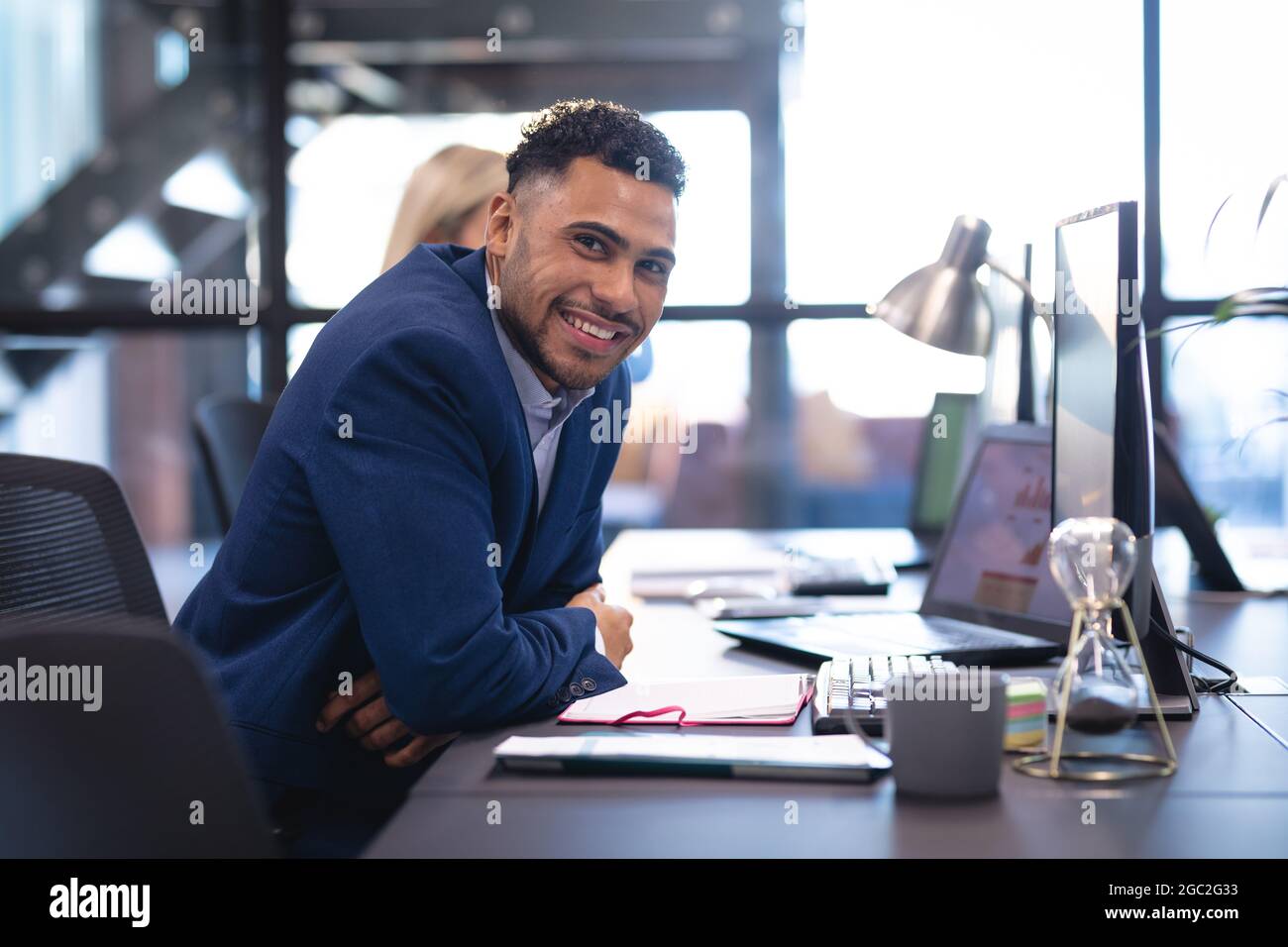 Porträt eines Geschäftsmannes mit einer Geschäftskollegin, die am Schreibtisch mit einem Laptop arbeitet Stockfoto