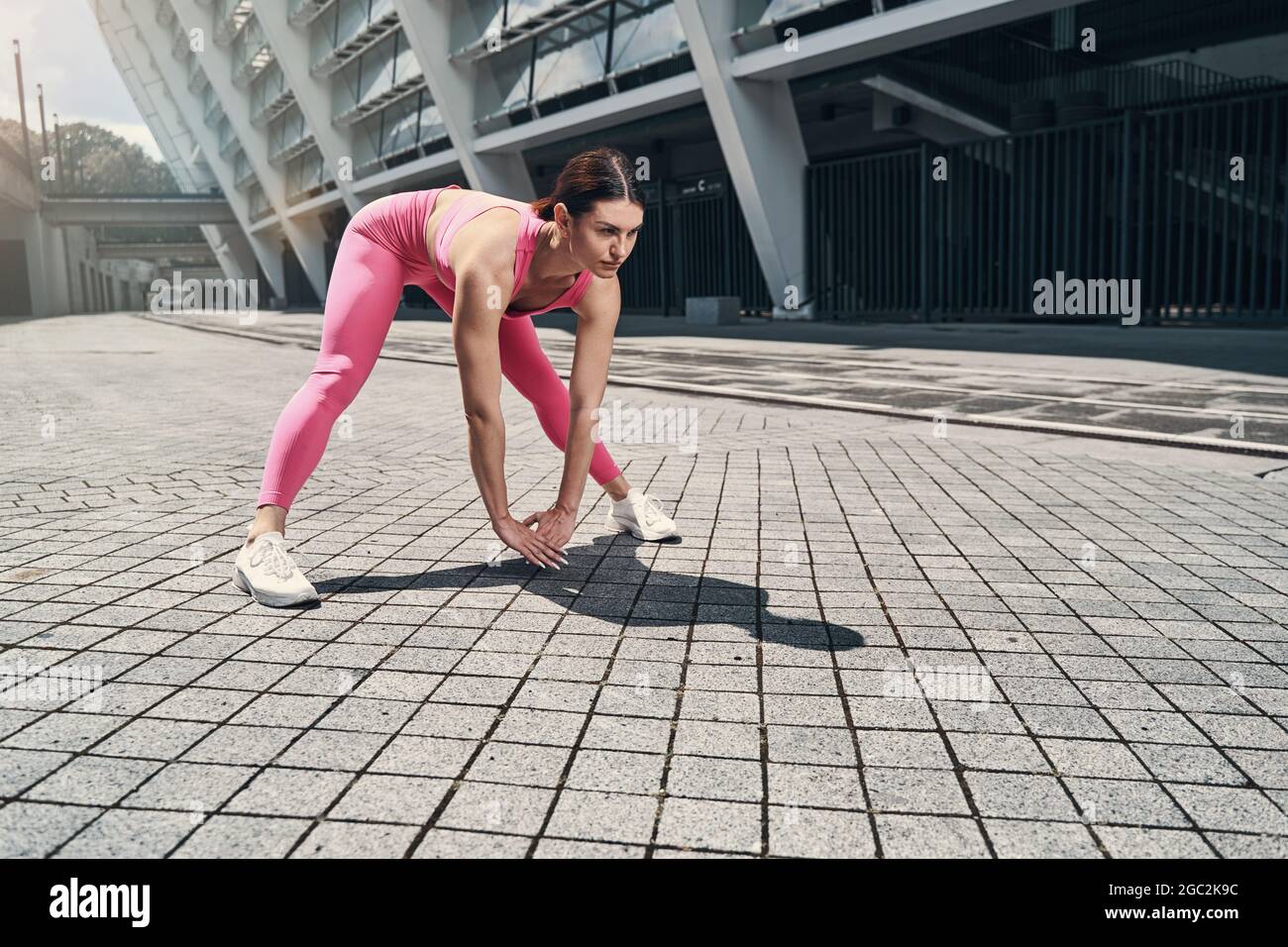 Sportliches Weibchen macht Vorwärtsbeuge und berührt den Boden Stockfoto