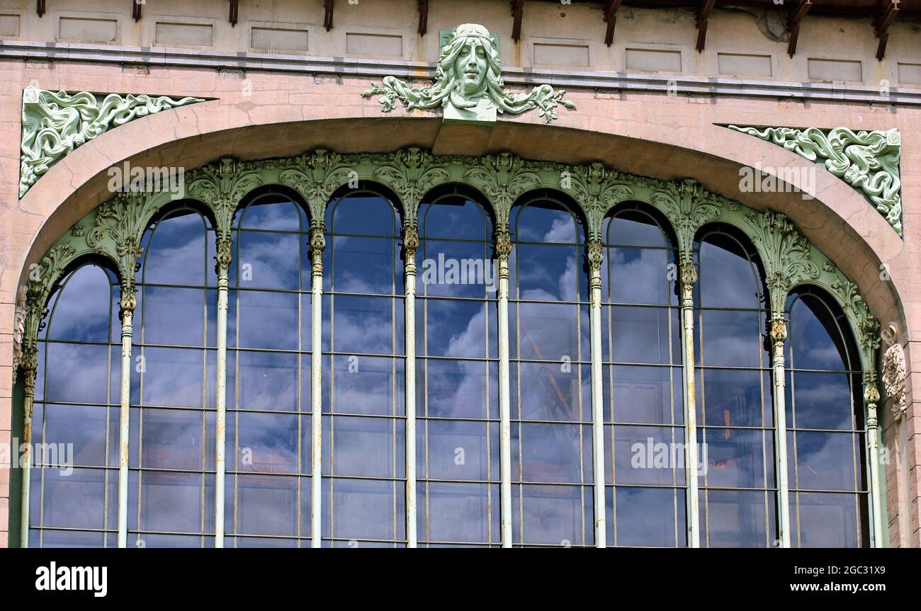 Frauenmaske - hohes Relief über dem Bogen der Glasfassade des frühen modernen Gebäudes Stockfoto