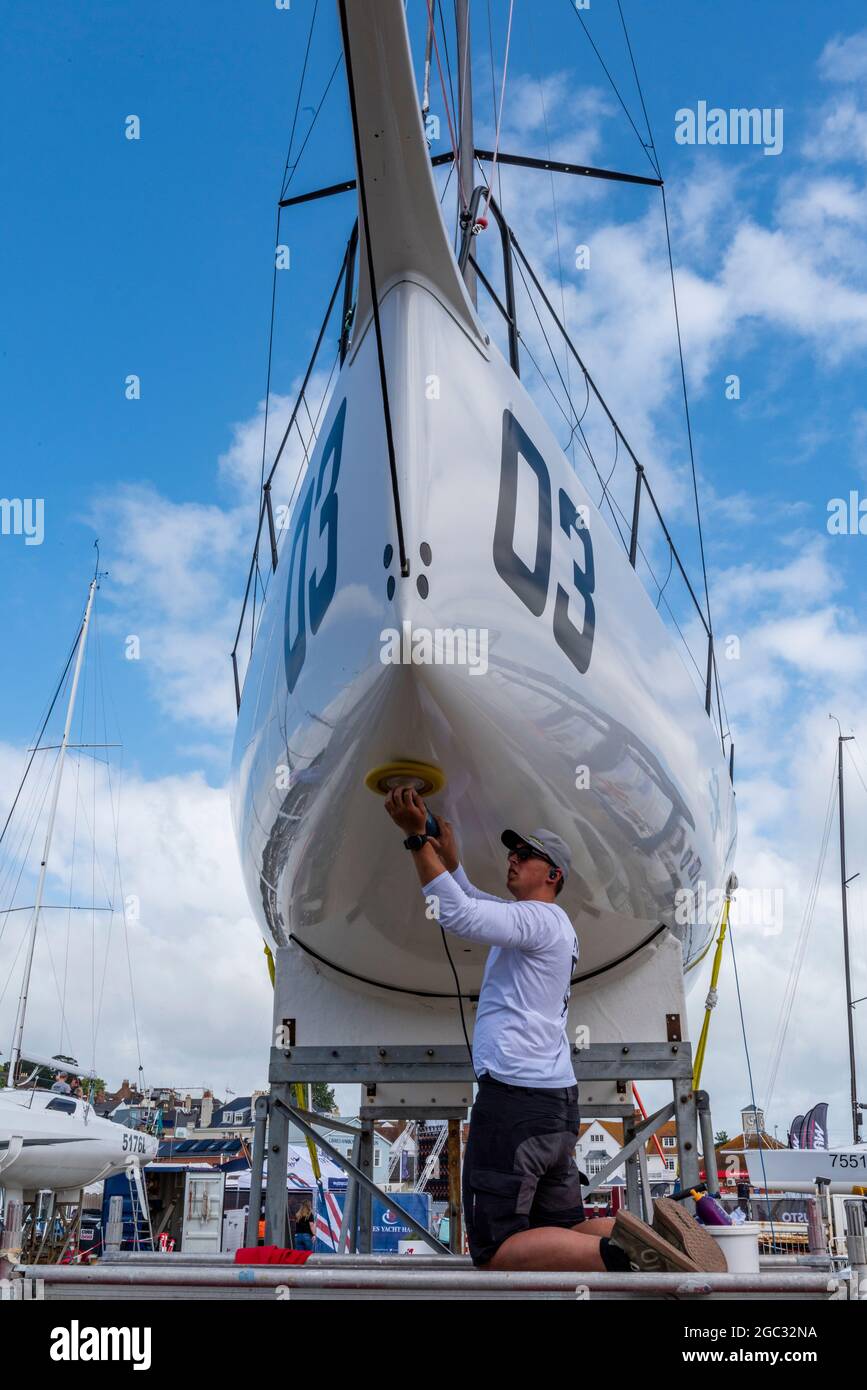 cowes Week, Insel wight, Mann Polierboot, Crew-Mitglied Reinigung Boot, Polieren Rumpf von Rennyacht, Segelregatta Wartung, Yachting Crew. Stockfoto