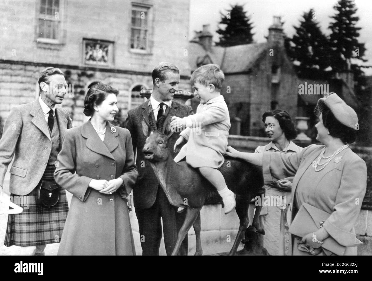Prinz Charles steht im Mittelpunkt, als er während eines Familientreffens im Balmoral Castle, Schottland, auf der Skulptur eines Hirsches sitzt. August 1951. Stockfoto
