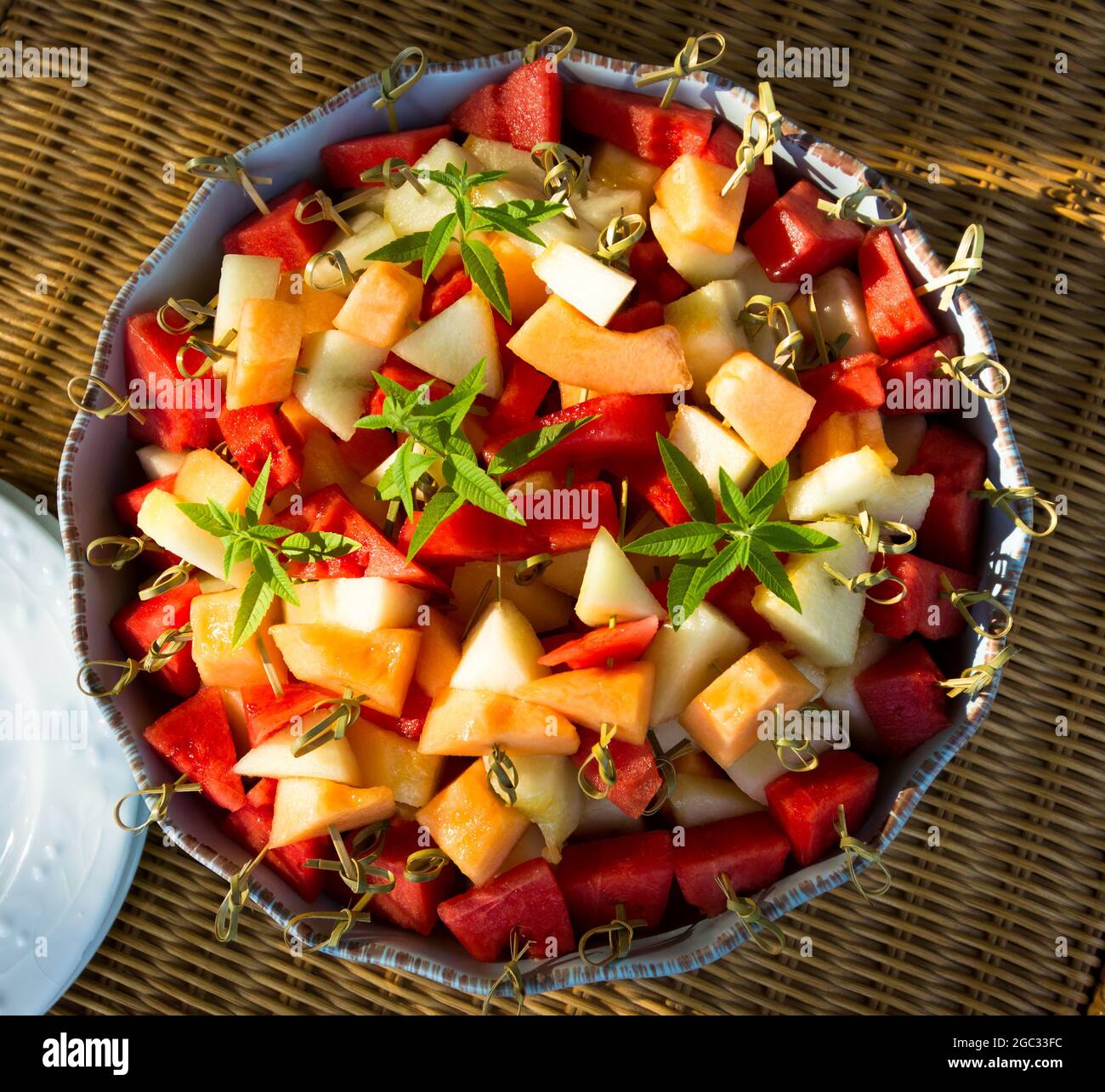 Große Schüssel mit frisch geschnittenem Obst, Melone, Wassermelone, auf Bambusstäbchen. Stockfoto