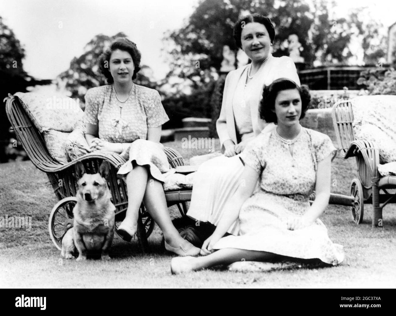 Die fahrbaren Sessel auf dem Rasen sind genau das Richtige, um einen ruhigen, sonnigen Nachmittag in der Royal Lodge, Windsor, zu genießen. Mit der Königin und den Prinzessinnen Elizabeth und Margaret ist Susan, ein Corgi (kleiner Welsh-Hund), Prinzessin Elisabeths Favorit - Juli 1946 Stockfoto