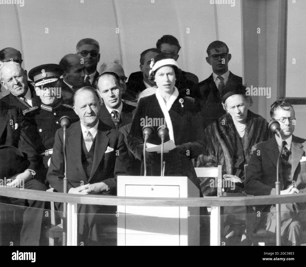 Die Königin hält ihre Rede, bevor sie den Schalter zieht, der Calder Hall in Betrieb genommen hat, das erste Atomkraftwerk der Welt in Vollmaßstab, in der Nähe von Sellafield, Cumberland 17. Oktober 1956 mit der Queen auf dem Podium sind Mr. R. A. Butler, Lord Privy Seal (links) und Sir Edwin Plowden, Vorsitzender der britischen Atomenergiebehörde (rechts). Die £16 Millionen 1/2 teure Anlage wird nun in das nationale Stromnetz eingespeist. Stockfoto