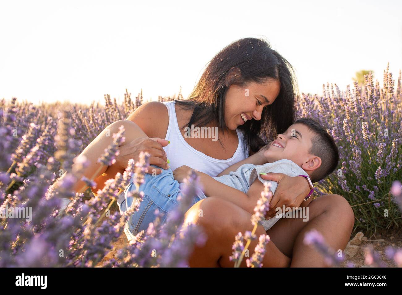 Die junge Latina spielt mit ihrem Sohn auf einem Feld aus Lavendelblüten. Familienleben in der Natur genießen Stockfoto