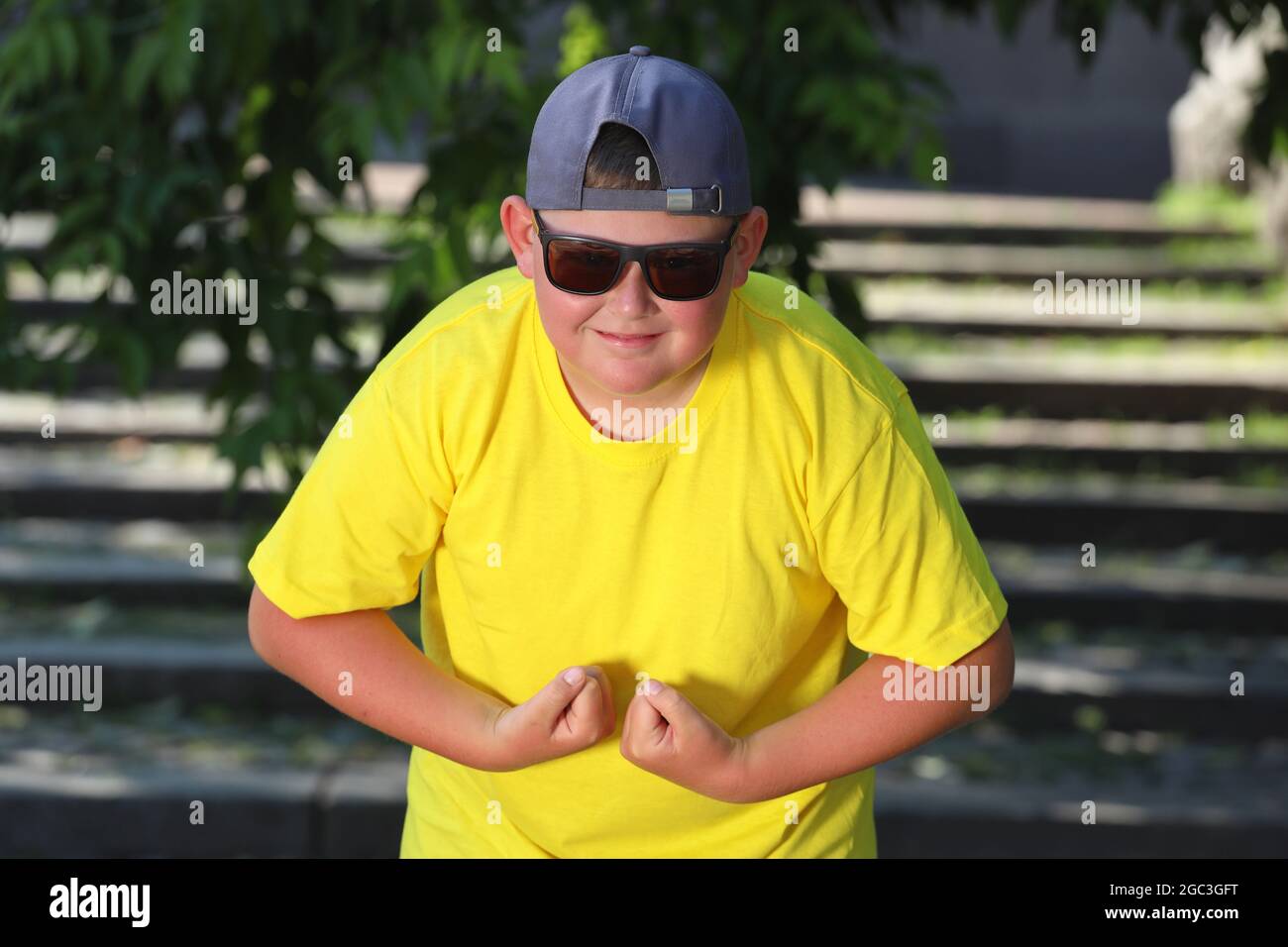 Ein großer Junge in einem gelben T-Shirt spannt seine Muskeln. Das Konzept der Körperpositivität. Hochwertige Fotos Stockfoto