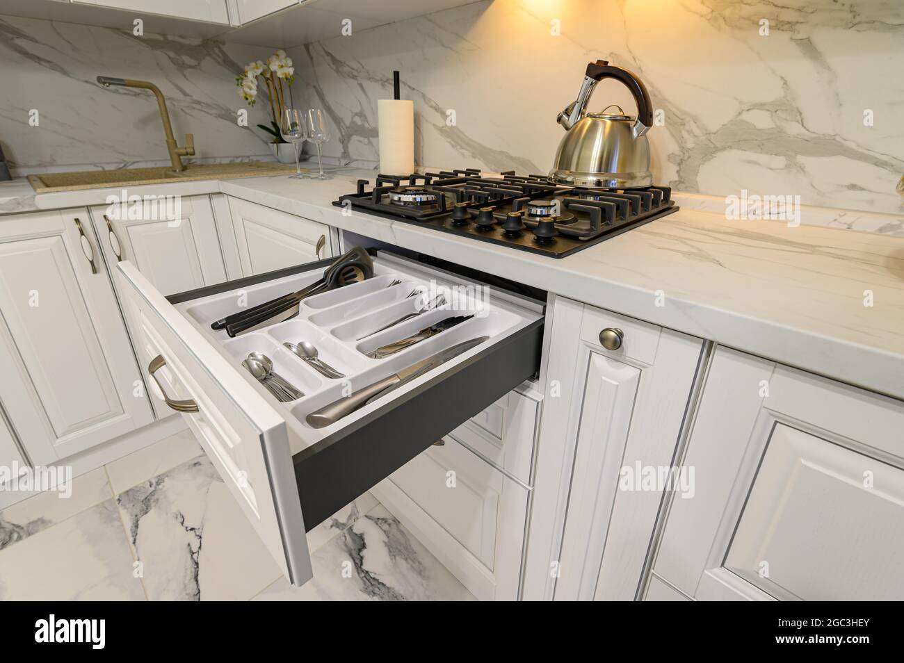 Offene Schubladen mit Geschirr in der modernen weißen Küche Stockfoto