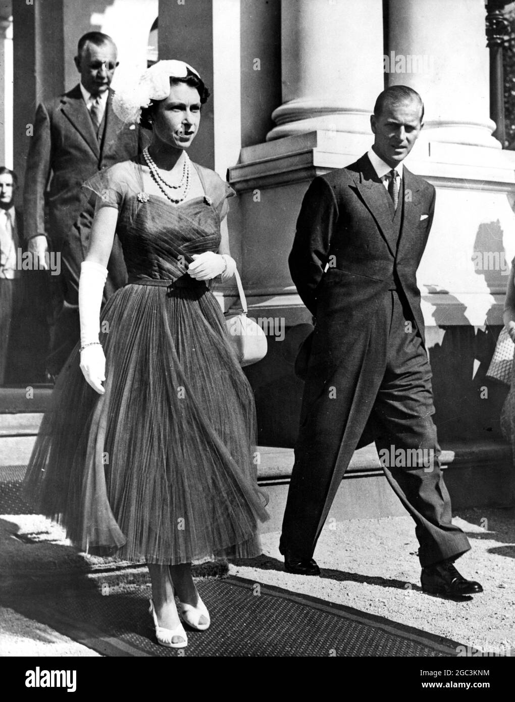 Königin Elizabeth II trägt ein Kleid aus reichem königsblauem Nylonnetz mit einem eng geflissenen Hemd und herzförmigem Ausschnitt, abgebildet mit dem Herzog von Edinburgh auf der Gartenparty im Government House in Melbourne. Februar 1954 Stockfoto