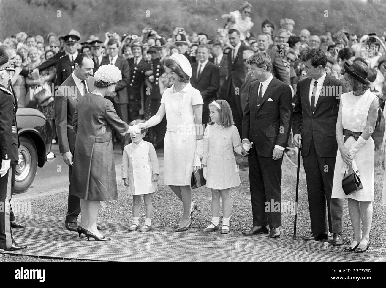 Jacqueline Kennedy begrüßt Königin Elizabeth II. Bei der Ankunft in Runnymede, Surrey. Mit Frau Kennedy sind ihre beiden Kinder Caroline (7) und John (4) . Die Königin enthüllt das Denkmal in Runnymede dem Ehemann von Frau Kennedy, dem verstorbenen US-Präsidenten John F. Kennedy. Ebenfalls anwesend sein wird der Bruder des verstorbenen Präsidenten, die Senatoren Edward und Robert Kennedy. 14 May 1965 Lord Harlech auf der linken Seite Stockfoto