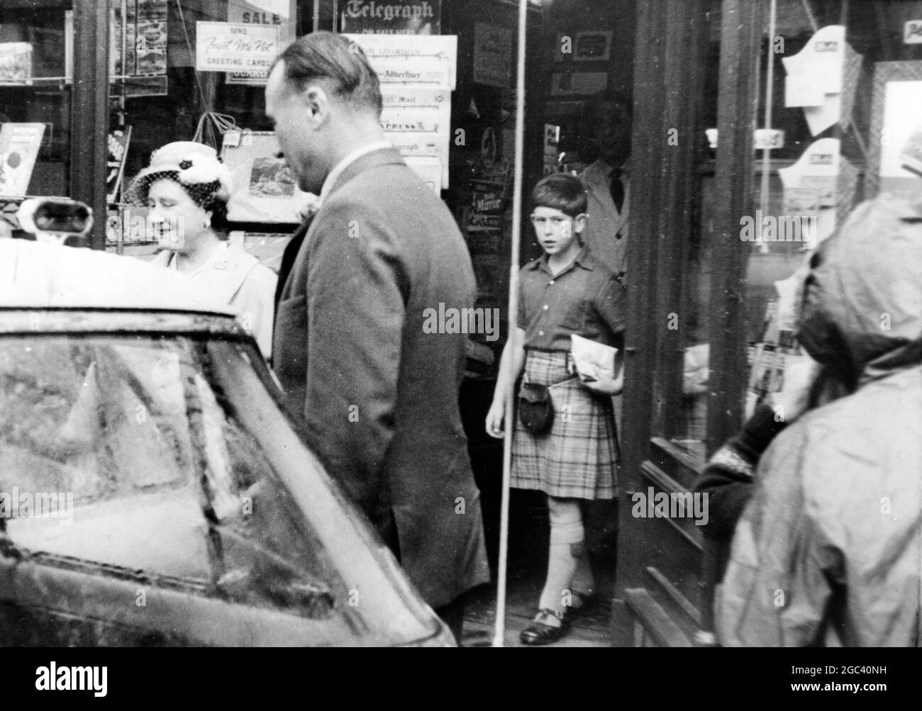 Ballater, Schottland - Prinz Charles, der einen Kilt trägt, verlässt während einer Shopping-Expedition mit der Queen Mother einen Angelgeschäft. 13. September 1959 Stockfoto