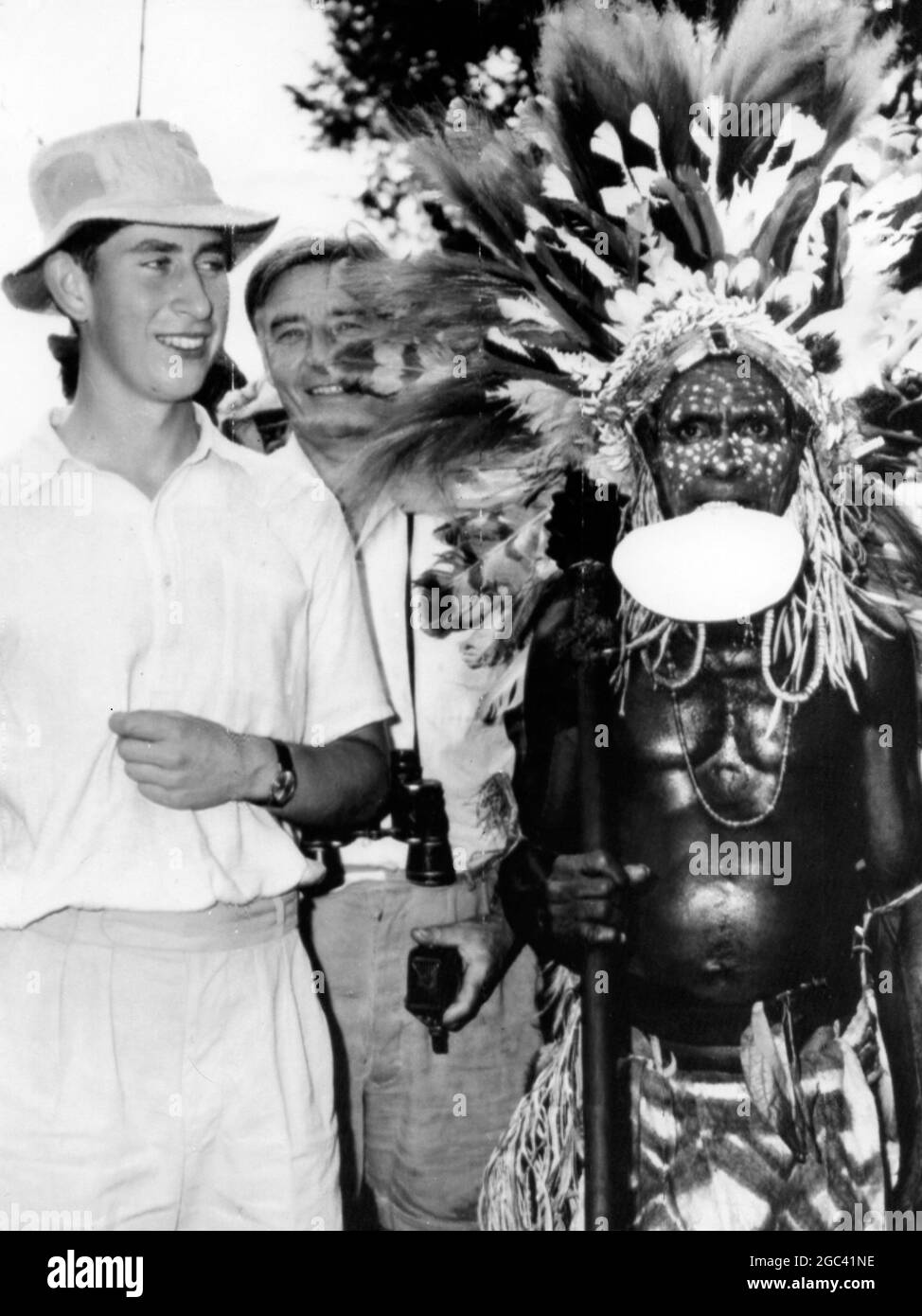 Prinz und der Krieger Prinz Charles steht mit einem gefiederten Kriegertänzer während des bunten Singes, bei dem er als erfolgreicher Kampfmann mit großem Mut am Fuße des Mount Lamington, Neuguinea, eingesetzt wurde. Die Tänzerin stellte dem Prinzen später eine Kette aus Wildschweinzähnen vor. Die Zeremonie wurde als Abschied von dem Prinzen abgehalten, der Papua verließ. 5 Mai 1966 Stockfoto