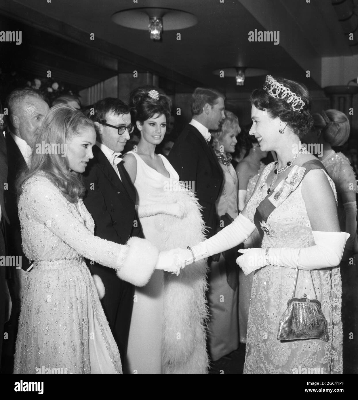 Queen Elizabeth II schüttelt sich die Hände mit Ursula Andress im Odeon Theatre, Leicester Square, London für die Royal Film Performance 1966, wo sie den Film Born Free in Aid of the Cinema and Television Benevolent Fund sehen soll. In der Linie ist Woody Allen und Raquel Welch . 14. März 1966 Stockfoto