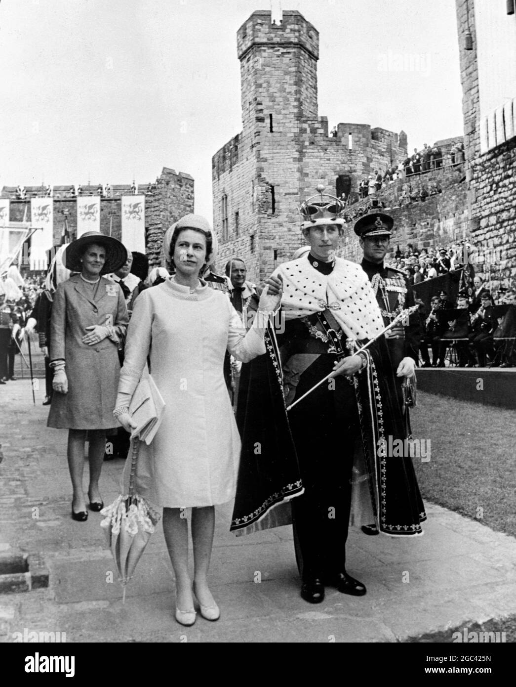 Ihre Majestät Königin Elisabeth II. Lächelt, als sie Prinz Charles in der Hand hält und ihn den Menschen als neuen 21. Prinz von Wales präsentiert. Sie werden nach der Investiturzeremonie gesehen, bei der Prinz Charles den gesamten Mantel der Royal Regalia und Ermine über seiner Militäruniform des 1. Bataillons des Royal Regiment of Wales trägt. Juli 1969 Stockfoto