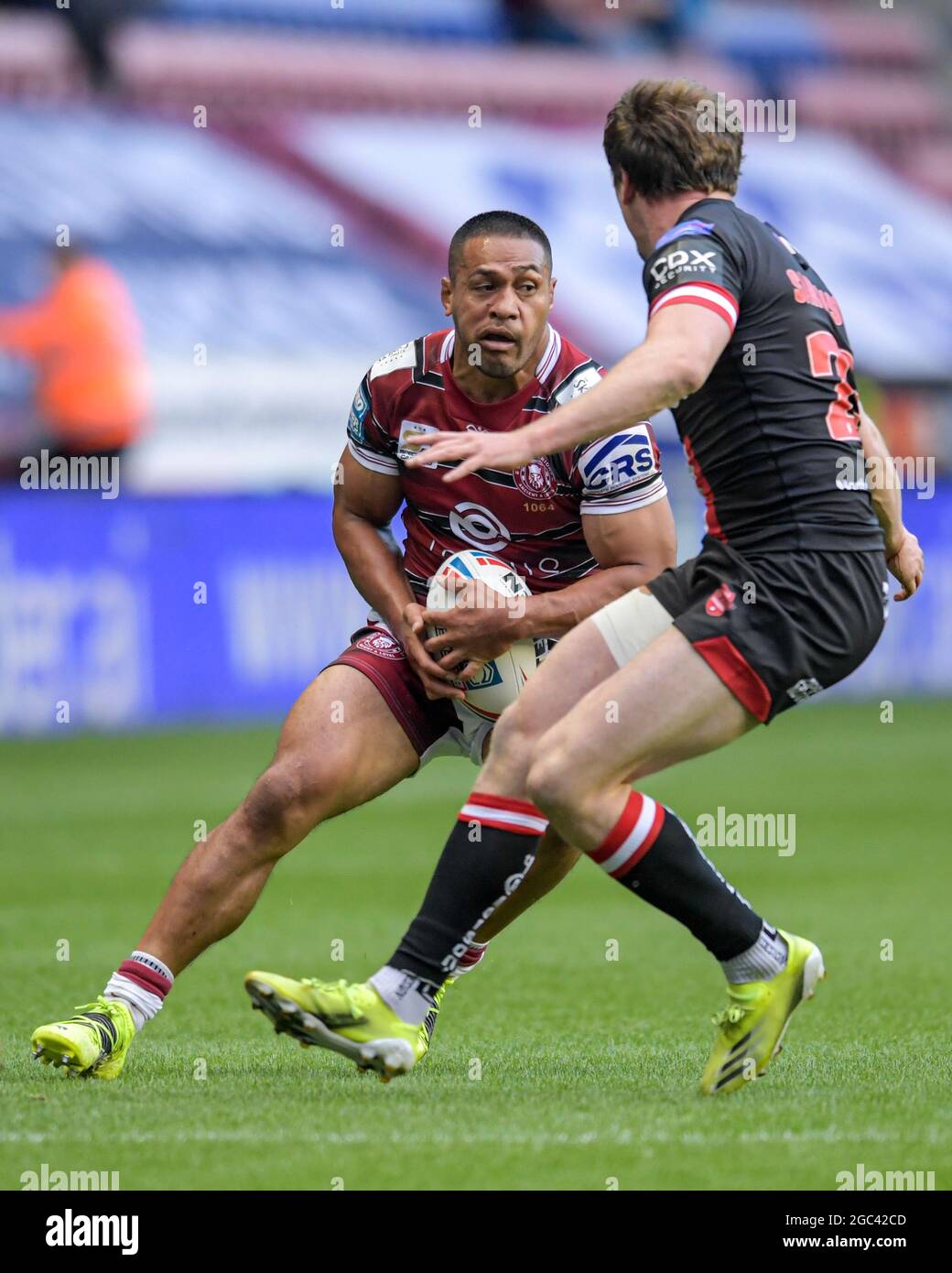 Willie Isa (11) von Wigan Warriors sucht einen Weg hinter Dan Sarginson (23) von Salford Red Devils Stockfoto