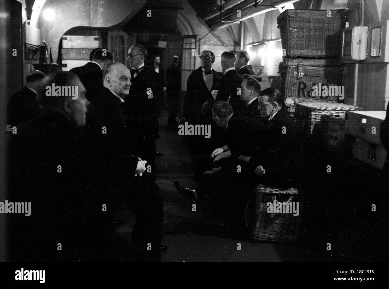 Hinter den Kulissen bei einem Staatsbankett. Bankett für Königin Elizabeth II. Im Mansion House, London nach ihrer Commonwealth Tour im Jahr 1954. Die Catering-Firma von Ring & Brymer (Birch's) Ltd hat die Verpflegung bei jedem Krönungsbankett der Corporation of London seit der Krönung von Königin Victoria übernommen und hat mehr gekrönte Köpfe als jedes andere Unternehmen auf der Welt betreut. 19. Mai 1954 Fotoshows: Zwischen den Kursen entspannen sich die Kellner im unterirdischen Gang vor den Küchen. Auf den Körpern sind die Initialen von Ring & Brymer zu sehen Stockfoto