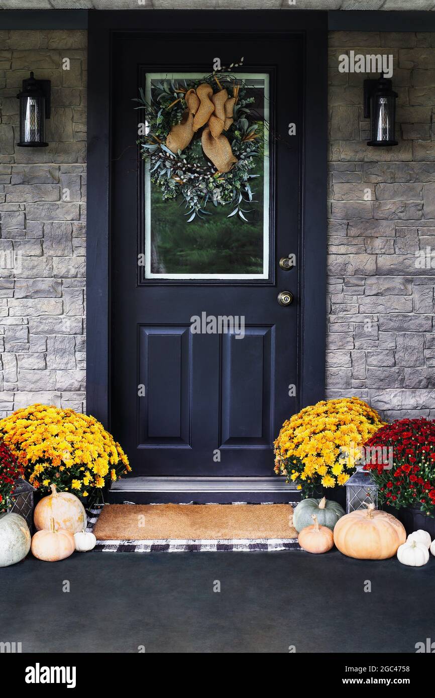 Veranda dekoriert für Thanksgiving Day mit hausgemachtem Kranz an der Tür. Erbstück Kürbisse, weiße, grüne und orange Kürbisse, und bunte Mütter Stockfoto