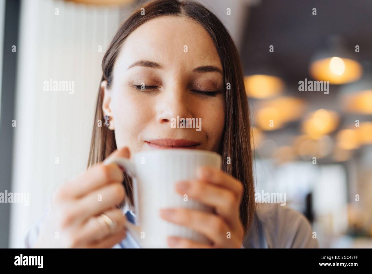 Attraktive Frau mit niedlichem Lächeln mit einem Kaffee beim Entspannen In Pause Stockfoto
