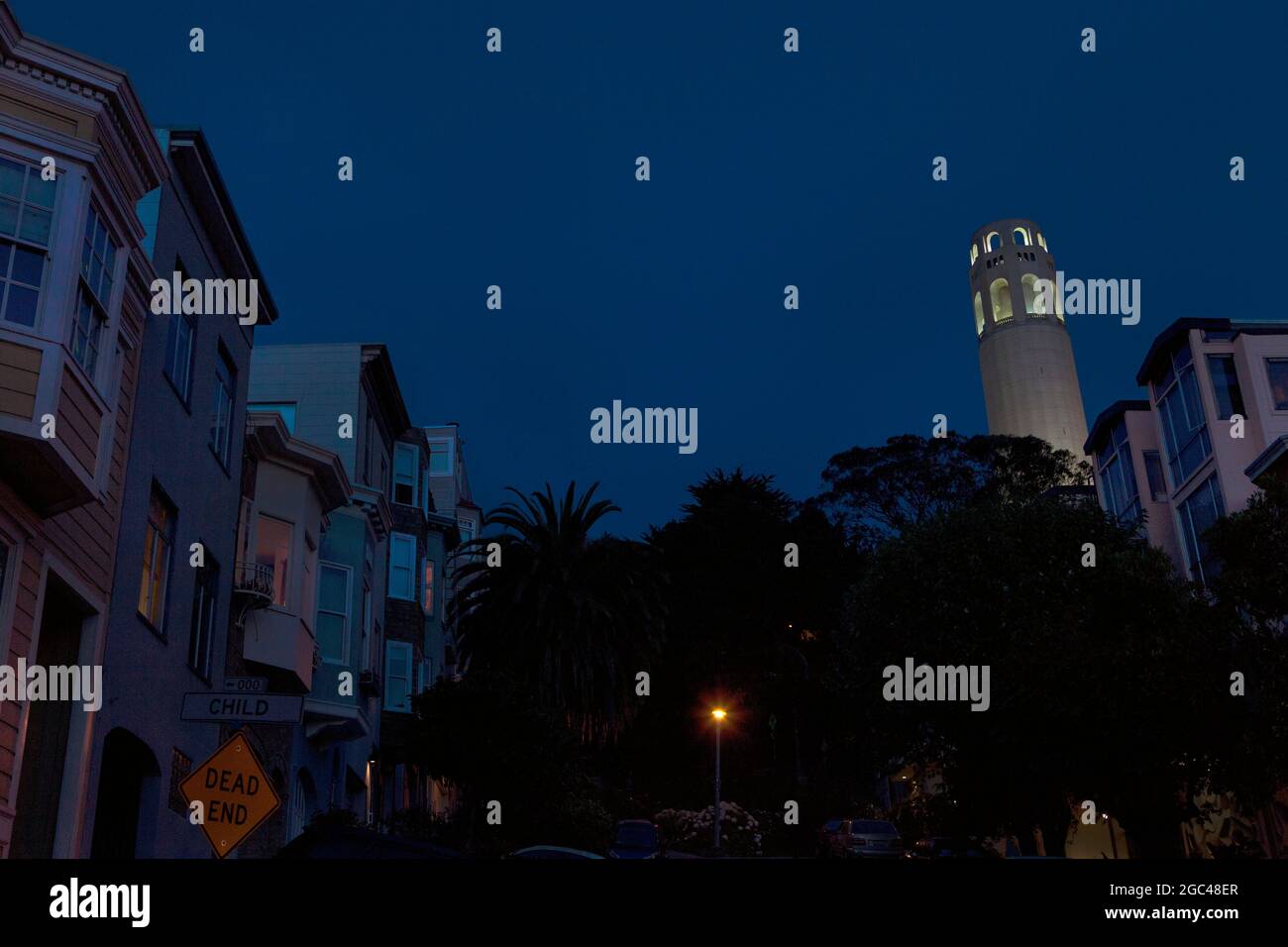 Häuser am Hang und Coit Tower am Abend, San Francisco, CA Stockfoto