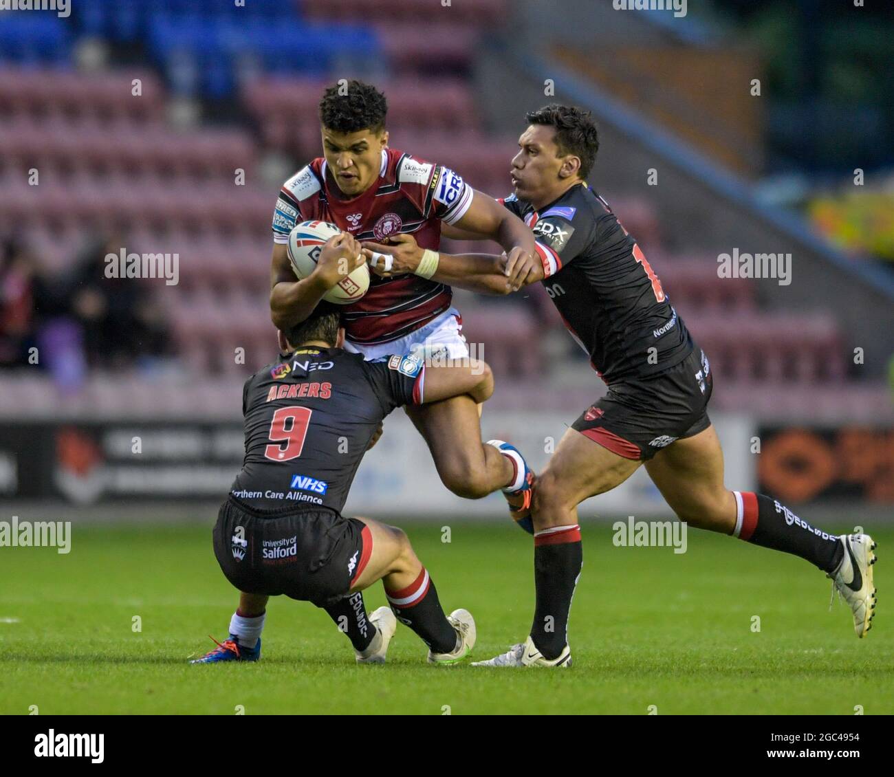 Kai Pearce-Paul (27) von Wigan Warriors wird von Andy Ackers (9) von Salford Red Devils und Elijah Taylor (13) von Salford Red Devils angegangen Stockfoto