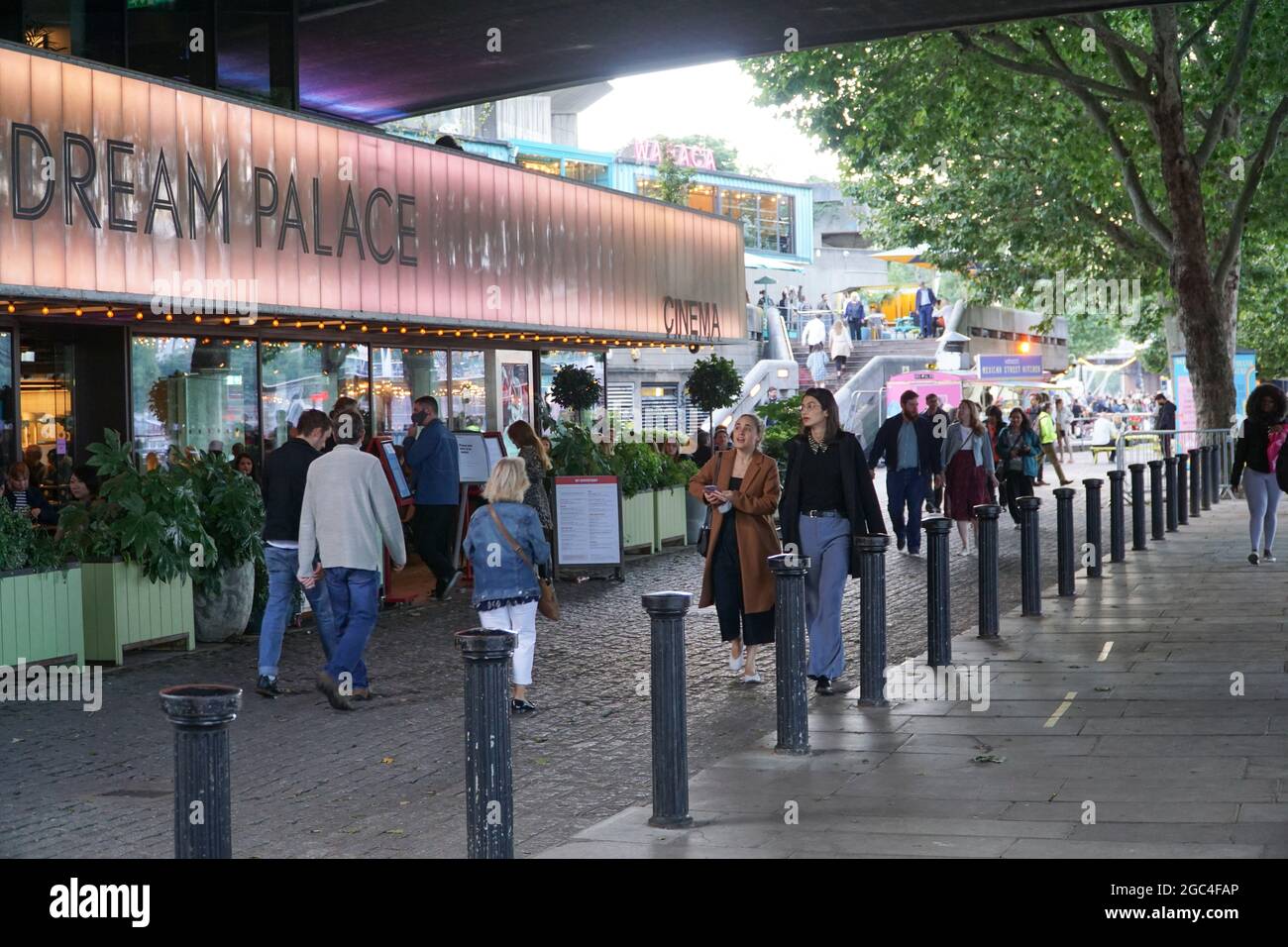 London, Großbritannien, 6. August 2021: Am Freitagseveining am Londoner South Bank werden die Massen von einer Reihe von Veranstaltungen im Freien begrüßt und Theater und Kino werden im National Theatre und BFI wieder aufgenommen. Eine Bühne im Freien mit DJ-Sets lädt Trinker und Tänzer zum Genießen ein, und Gäste nehmen Tische im Freien ein, wenn sich der Regen für einen sonnigen Sommerabend klärt. Einige Leute tragen Masken im Freien, aber die meisten tragen sie nur im Innenbereich oder in öffentlichen Verkehrsmitteln. Anna Watson/Alamy Live News Stockfoto