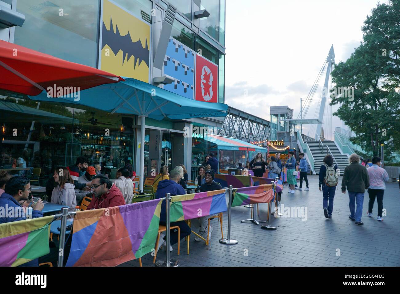 London, Großbritannien, 6. August 2021: Am Freitagseveining am Londoner South Bank werden die Massen von einer Reihe von Veranstaltungen im Freien begrüßt und Theater und Kino werden im National Theatre und BFI wieder aufgenommen. Eine Bühne im Freien mit DJ-Sets lädt Trinker und Tänzer zum Genießen ein, und Gäste nehmen Tische im Freien ein, wenn sich der Regen für einen sonnigen Sommerabend klärt. Einige Leute tragen Masken im Freien, aber die meisten tragen sie nur im Innenbereich oder in öffentlichen Verkehrsmitteln. Anna Watson/Alamy Live News Stockfoto