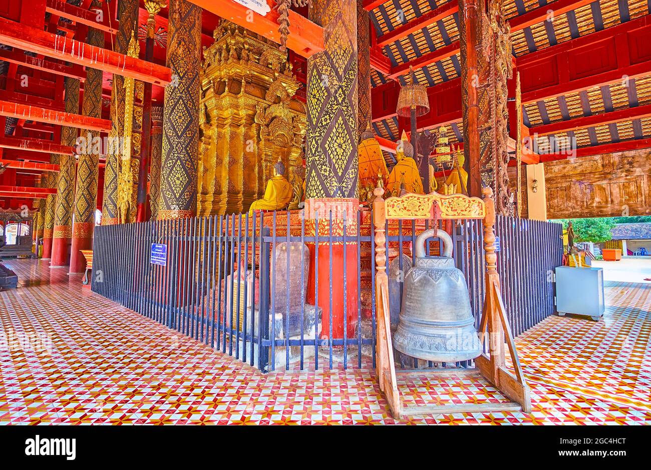 Die alte rituelle Glocke an den Teakholzsäulen von Viharn Luang im Wat Phra That Lampang Luang Tempel, Lampang, Thailand Stockfoto