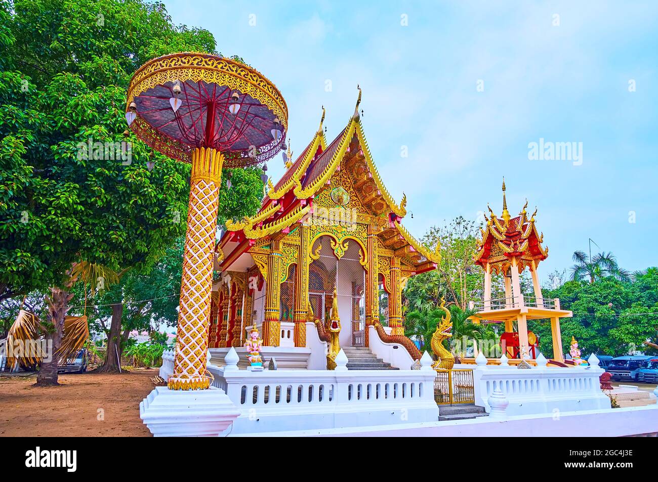 Der szenische chatra-zeremonielle Regenschirm, die Viharnhalle und ein Glockenturm des Wat Sangkharam Temple (Pratu Lee), Lamphun, Thailand Stockfoto