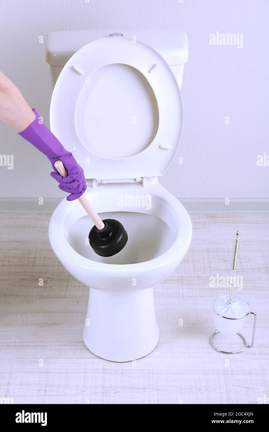 Frau verwendet ein Kolben eine WC-Schüssel in einem Bad zu reinigen  Stockfotografie - Alamy