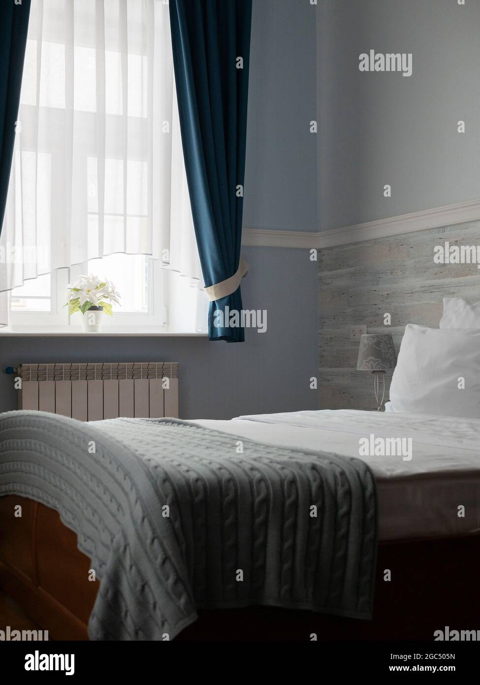 Bett mit weißen Kissen und blauen karierten Decken. Wunderschönes und gemütliches Hotelzimmer. Haus- oder Hotelschlafzimmer Stockfoto
