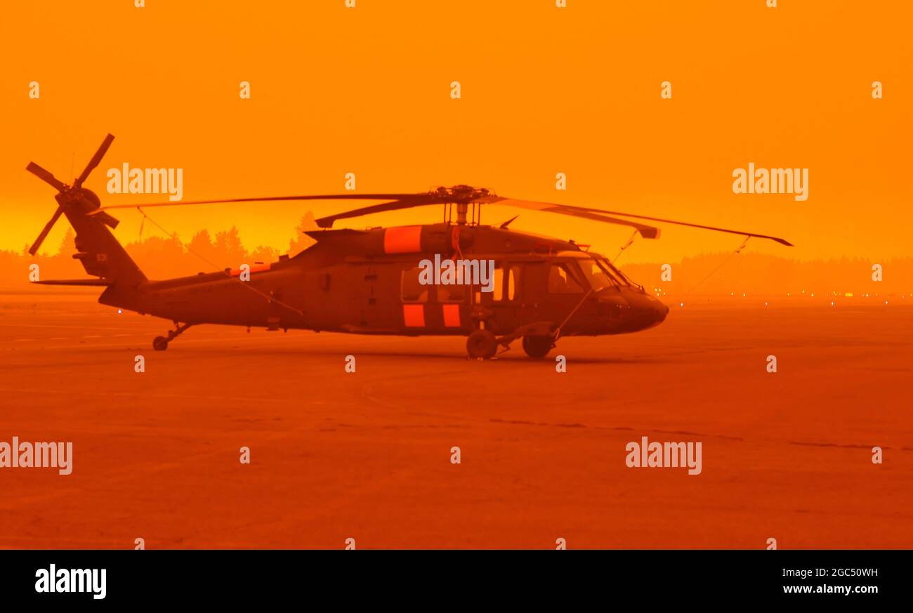 Am 9. September 2020 wartet ein Hubschrauber der Army National Guard UH-60M Black Hawk auf dem Asphalt in starkem Rauch auf dem Aurora State Airport in der Nähe von Aurora, Oregon. Die Flugbesatzungen der Gulf Company der Oregon Army National Guard, des 1. Bataillons, des 189. Luftfahrtregiments aus Salem, Oregon, wurden zur Unterstützung von staatlichen und lokalen Beamten gerufen, da beispiellose Feuerbedingungen Evakuierungen im ganzen Staat erzwangen. Seit Mitte August haben Wachhubschrauber bei den Waldbränden in Oregon mehr als 22,000 Gallonen Wasser abgeworfen. (Foto der Nationalgarde von Maj. Leslie Reed) Stockfoto