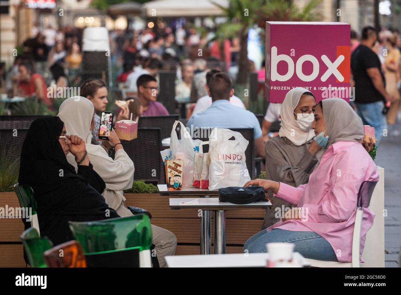 Bild einer jungen Frau aus dem Nahen Osten, die während des Coronavirus 2020 2021 in einem Café in Belgrad, Serbien, in einer schützenden Gesichtsmaske sitzt Stockfoto