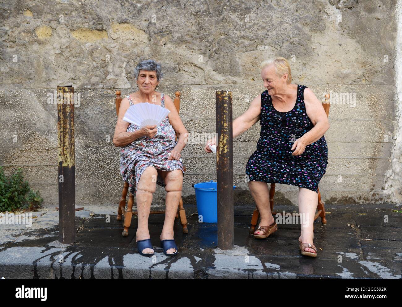 Juli 2015, Neapel Italien. Ältere italienische Frauen sitzen draußen auf der Straße mit einem Eimer Wasser, um bei der sengenden Hitze zu helfen. Stockfoto