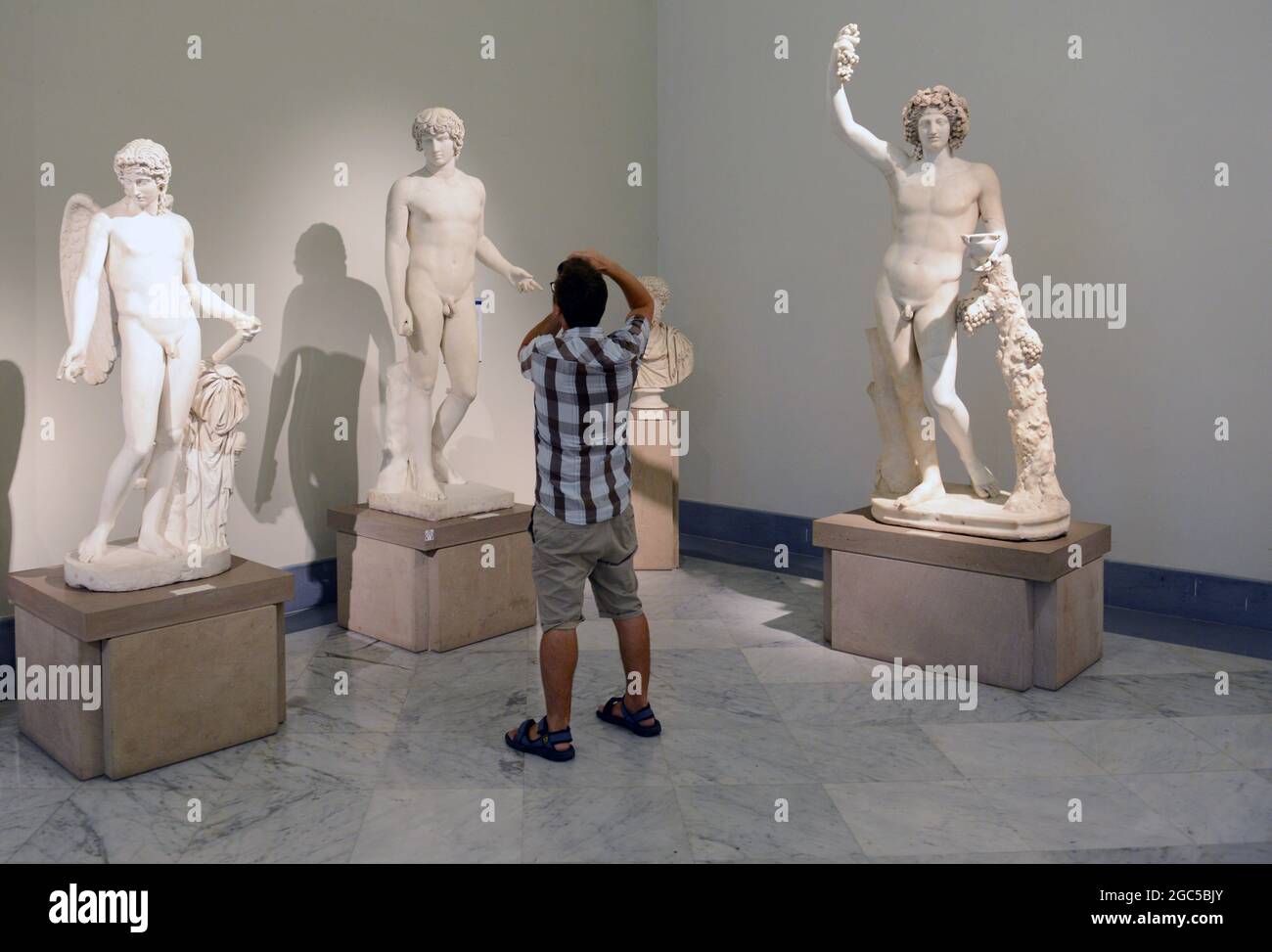 Ein Tourist, der eine Aufnahme von antiken römischen Marmorskulpturen im Nationalen Archäologischen Museum in Neapel, Italien, macht. Stockfoto