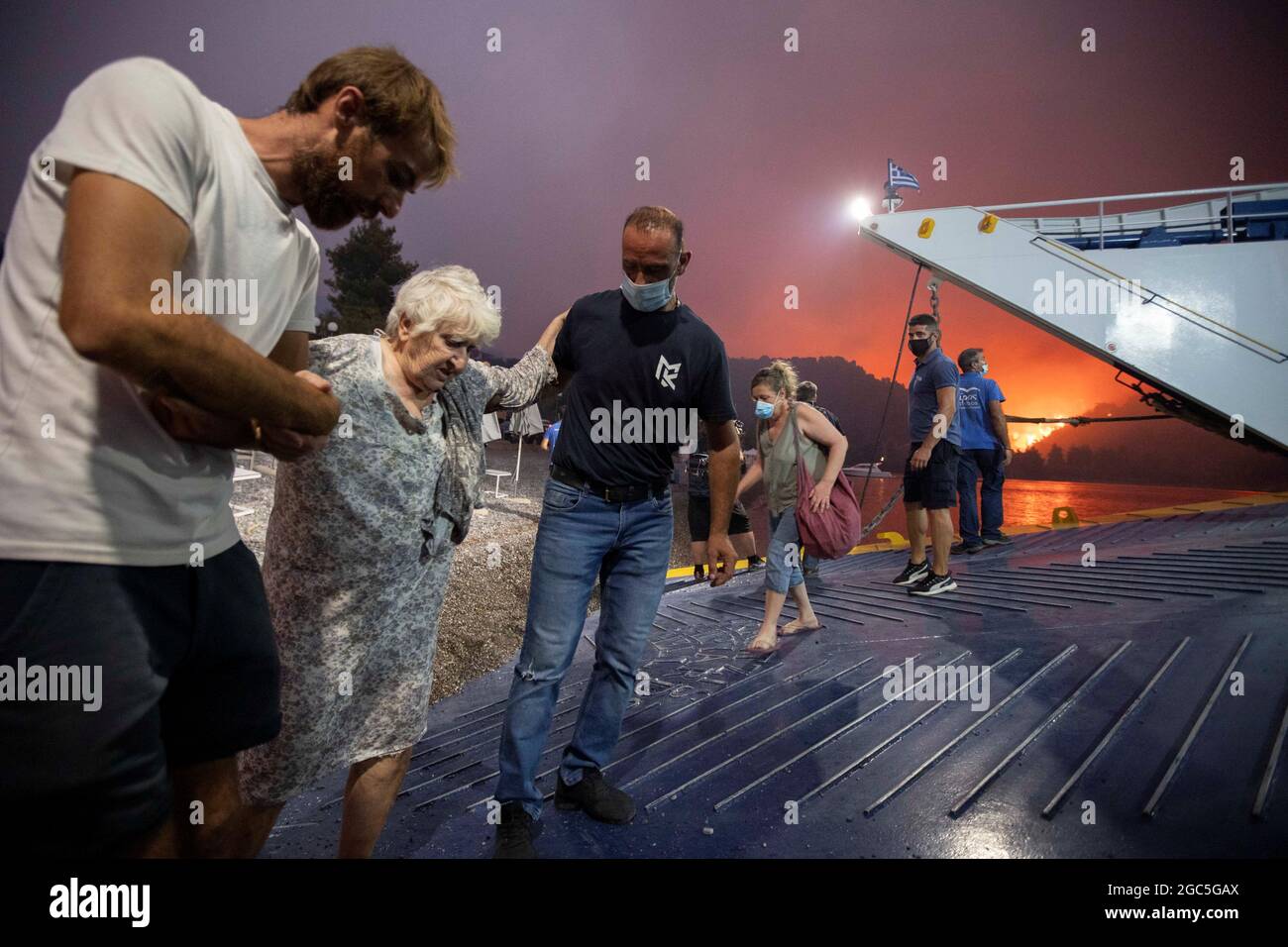 Während der Evakuierung besteigen Menschen eine Fähre, als im Dorf Limni auf der Insel Evia, Griechenland, ein Waldbrand brennt, 6. August 2021. Bild aufgenommen am 6. August 2021. REUTERS/Nicolas Economou Stockfoto