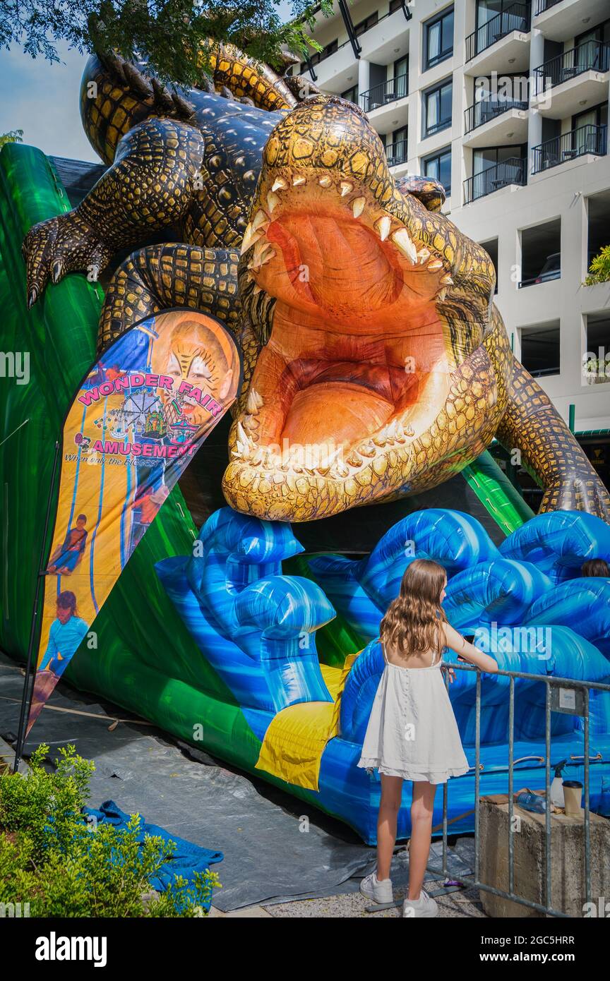 Ein junges Mädchen wartet geduldig auf die farbenfrohe Krokodilrutsche bei der Eröffnung des neuen Esplanade-Vorplatzes in Cairns, Queensland, Australien. Stockfoto