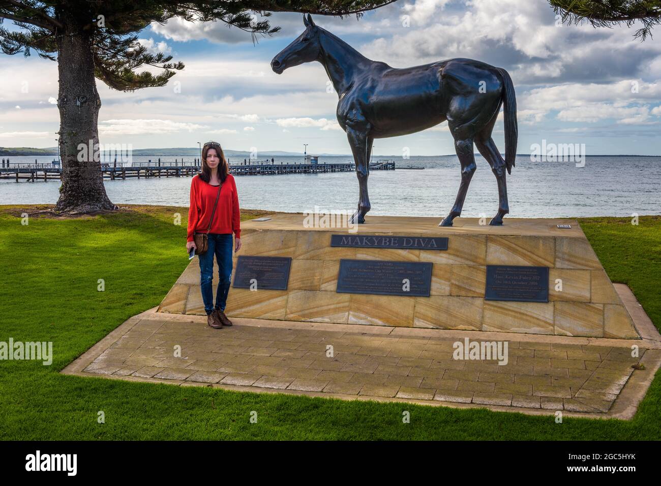 Eine weibliche Touristen steht neben der Bronzeskulptur der Rennpferdelegende Makybe Diva in Port Lincoln in Südaustralien. Stockfoto