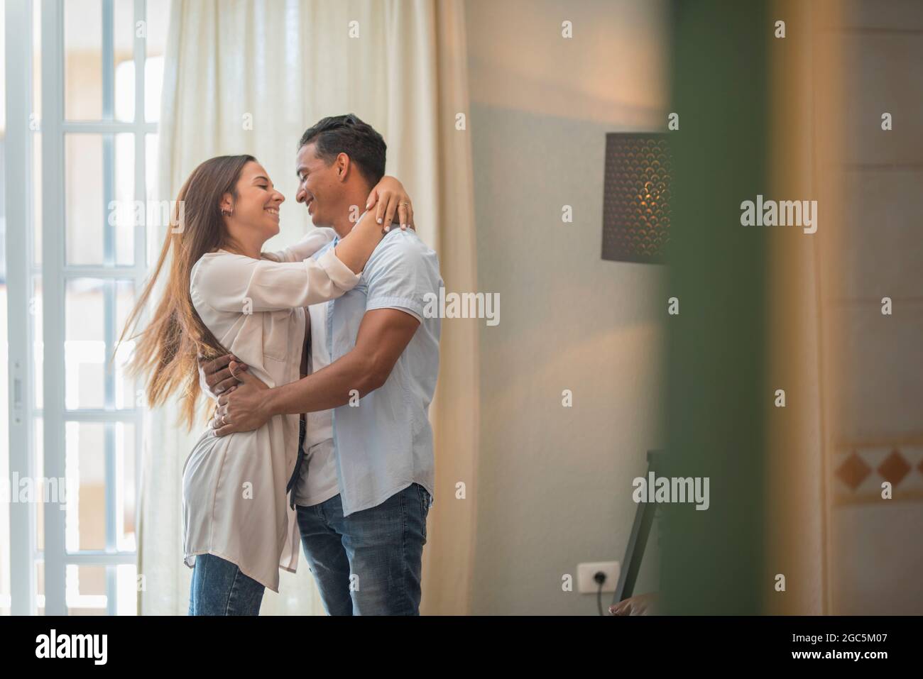 Fröhliche gemischte Ethnie zu Hause Fühlen Sie sich aufgeregt tanzen und halten mit Spaß, lächelnd überglücklich Paar genießen Jubiläum wirbeln und d feiern Stockfoto