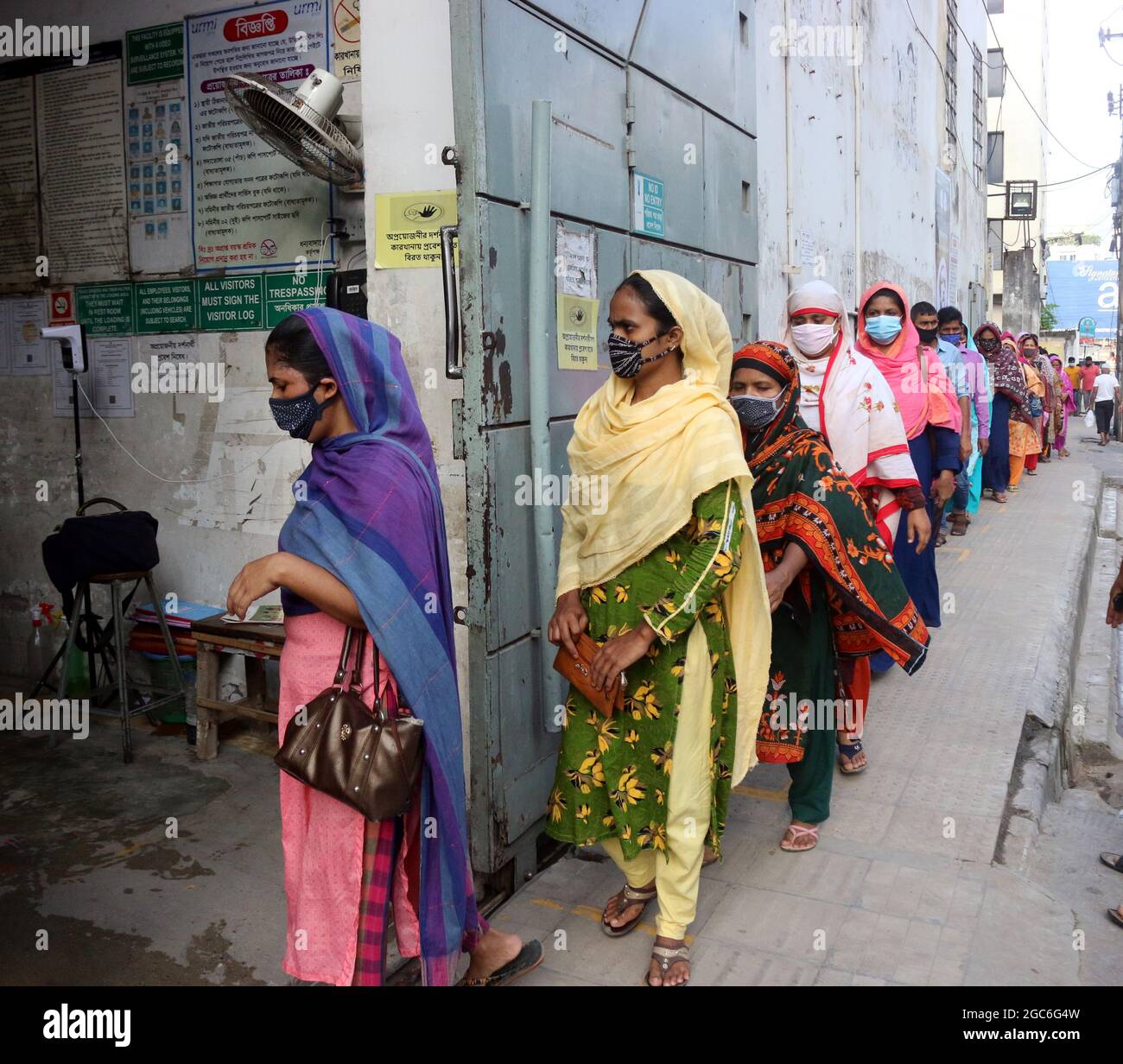 05,2021. August,Dhaka,Bangladesch: Sicherheitsmitarbeiter überprüfen die Körpertemperatur von Bekleidungsarbeitern, bevor sie nach Fakt über Kleidungsstücke in eine Bekleidungsfabrik eintreten Stockfoto