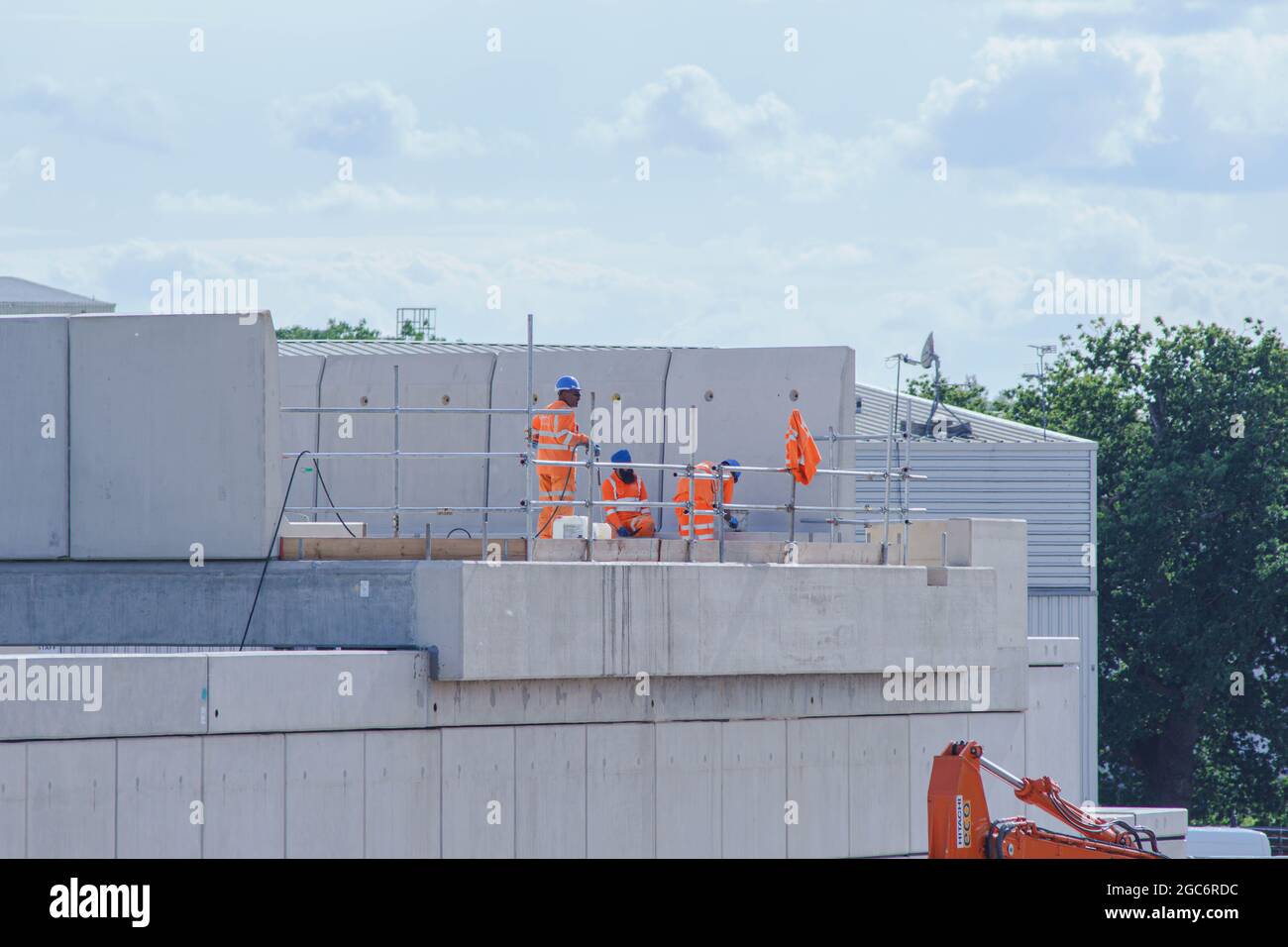Arbeiter in orangefarbenen Neon-Sicherheitsanzügen arbeiten an der Konstruktion eines Überflugs. Stockfoto
