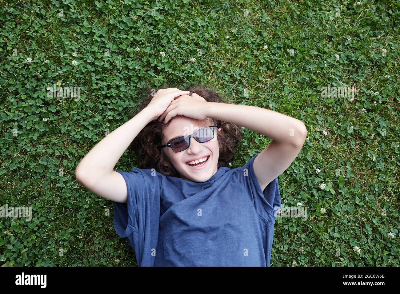 Junge im Gras liegend und lachend Stockfoto