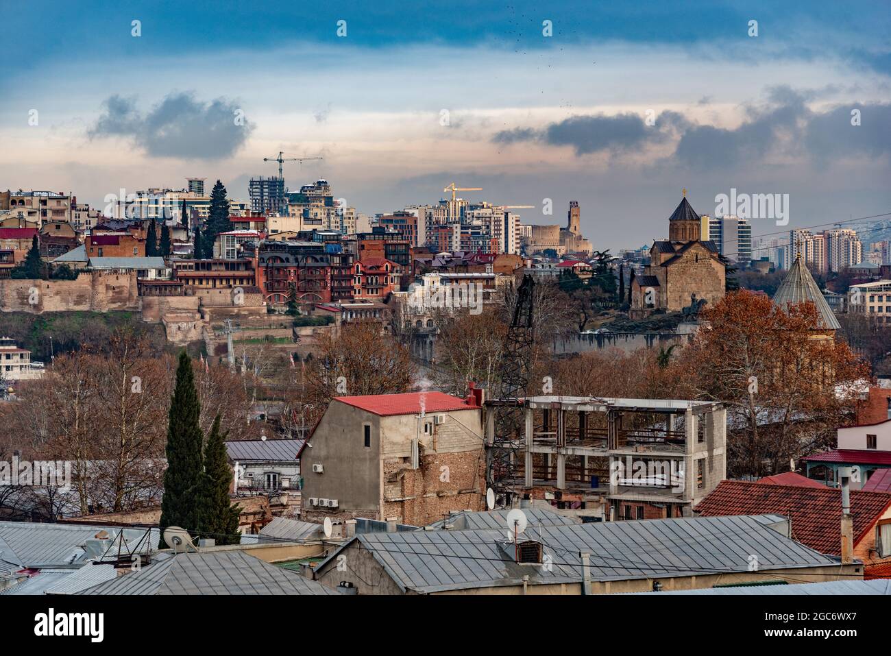 Blick von der Dachterrasse auf die Altstadt von Tiblisi, Georgiens Hauptstadt, im späten Winter, mit Schneestauben auf Dächern und Hängen und dramatischem Himmel Stockfoto