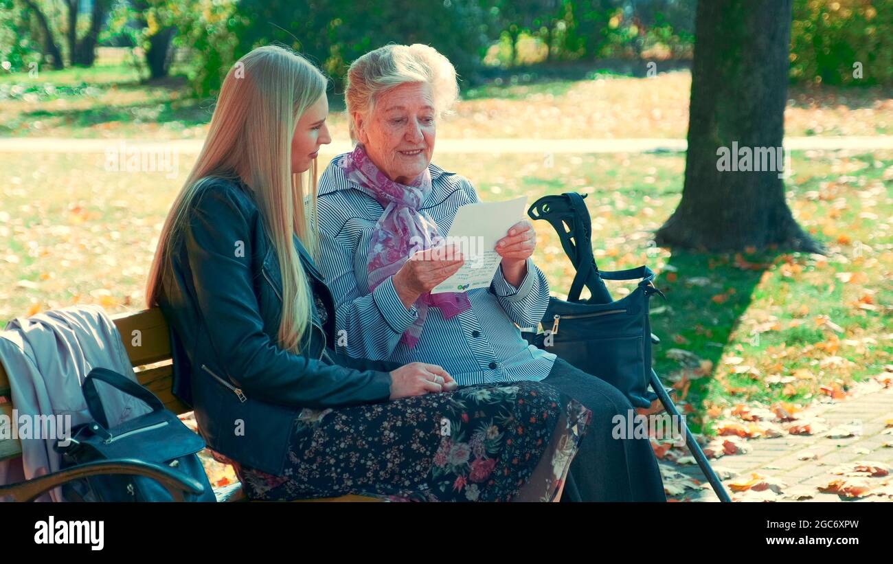 Voller Schuss von alter Frau, die einen Brief an die hübsche junge Frau im Park liest. Sie las eine interessante Geschichte ihres Lebens. Stockfoto