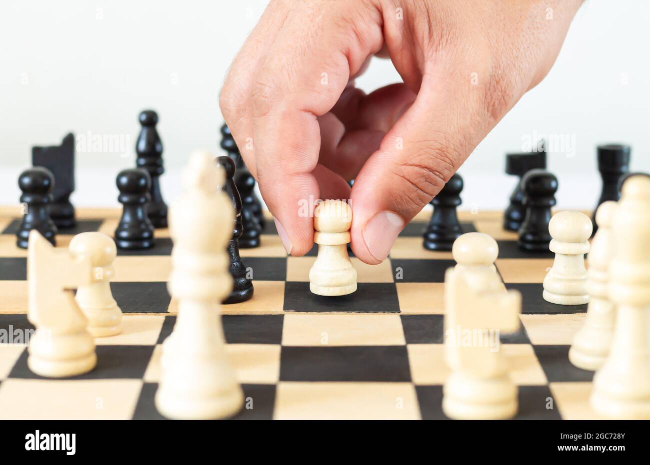 Mann bewegt Schachfigur im Spiel auf Schachbrett. Strategie, Taktik, Geschäfts- oder Führungskonzept Stockfoto