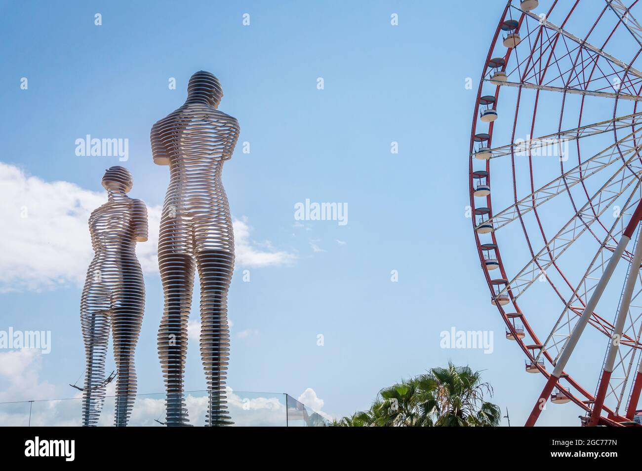 Batumi, Georgia - 2. Juli 2021: Ali und Nino Statue und das Riesenrad in Batumi, Adjara, Georgia. Sich aufeinander zu bewegen berühmte Skulpturen von Mann und Frau in der Liebe. Beliebte Touristenattraktion Stockfoto