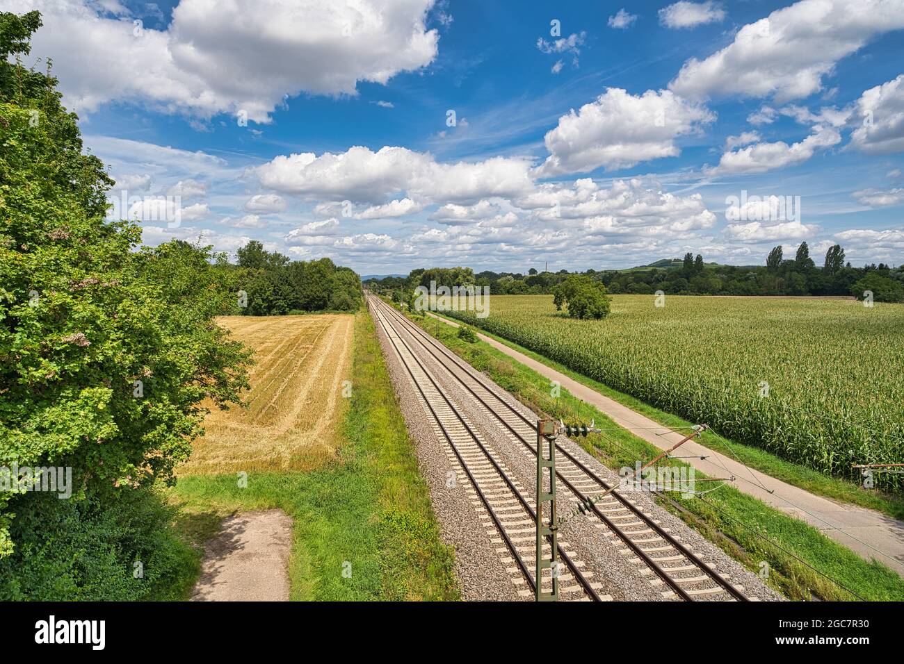 Gleise liegen parallel im Gleisbett, im Hintergrund eine wunderschöne Landschaft mit weißen Wolken und blauem Himmel Stockfoto